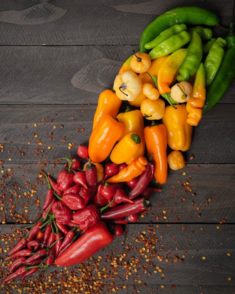 Mild, medium, and hot peppers arranged from green and yellow to deep red