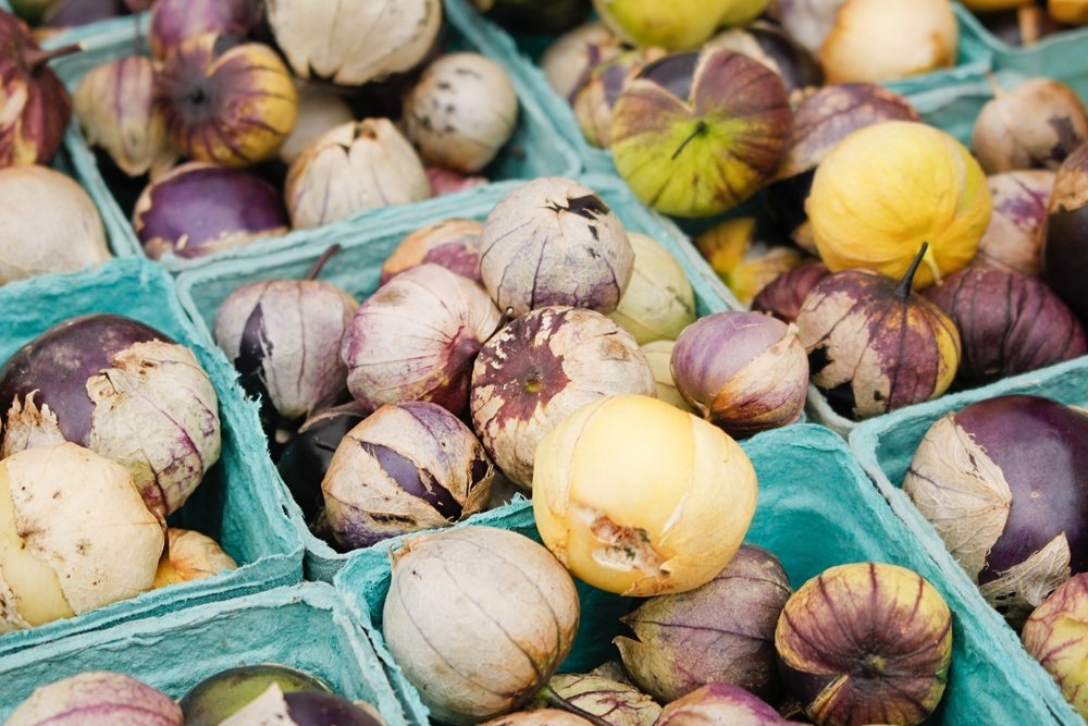 Purple and yellow tomatillos in papery husks displayed at a market