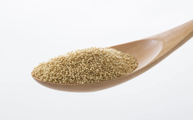 Small pale amaranth grains collected in a wooden spoon.