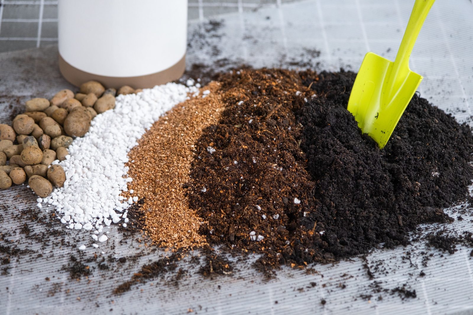 Separate piles of perlite, vermiculite, organic growing medium, and drainage material for potting mix