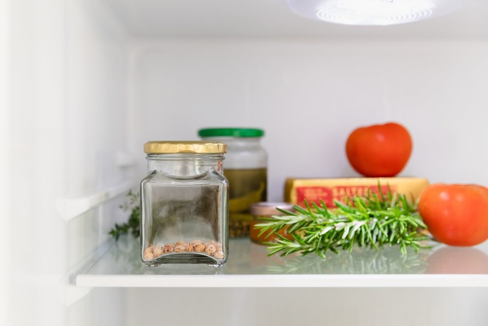 Labeled seeds stored in a glass jar on a refrigerator shelf