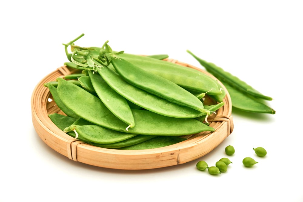 Flat snow-pea pods arranged in a harvest basket