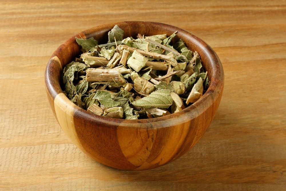 Dried lemon balm leaves and stems in a wooden bowl