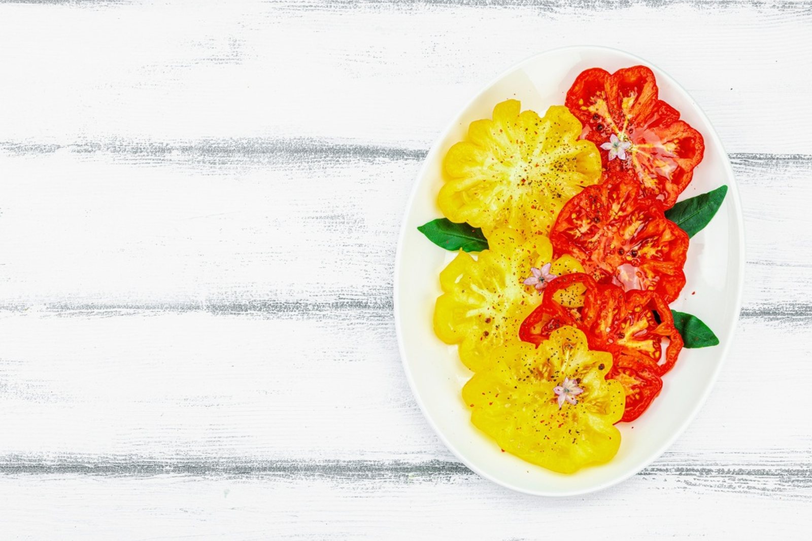 Yellow and red ribbed tomato slices arranged on a plate