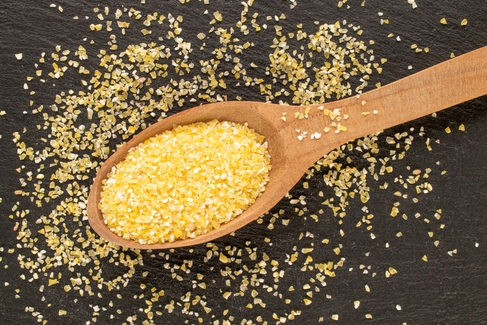 Coarse yellow corn grits in a wooden spoon