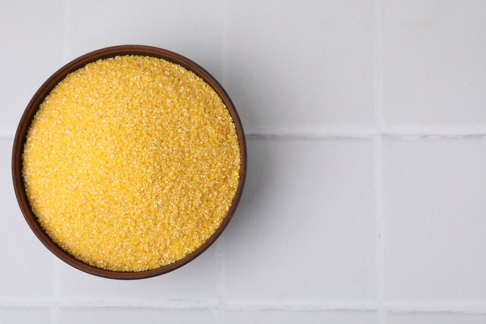 Bowl of raw yellow cornmeal on a light surface