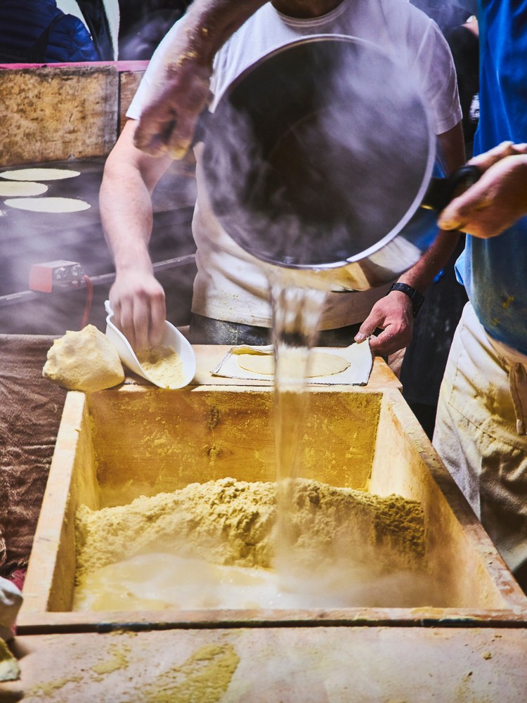 Hot liquid being poured into ground corn during food preparation