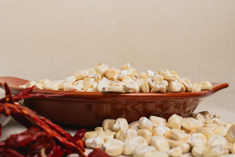 Prepared white hominy kernels beside dried red chiles