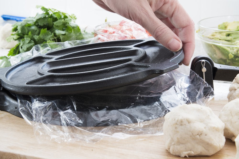 Masa balls beside a cast-iron tortilla press