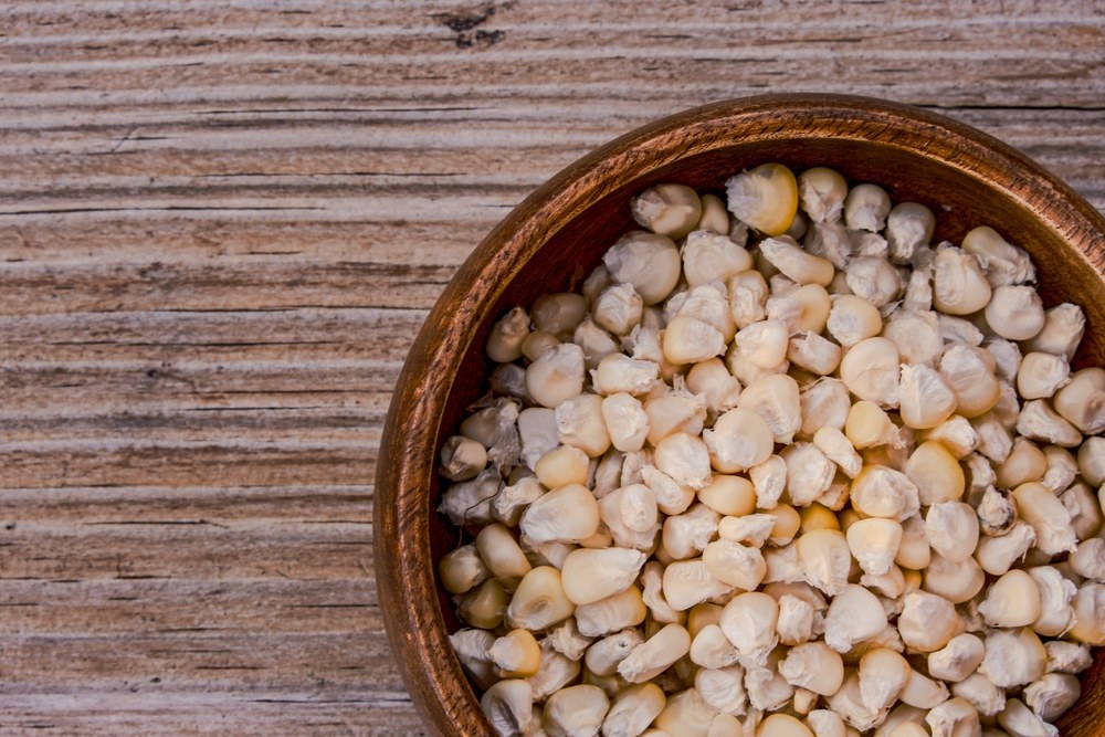 Dry white corn kernels in a wooden bowl