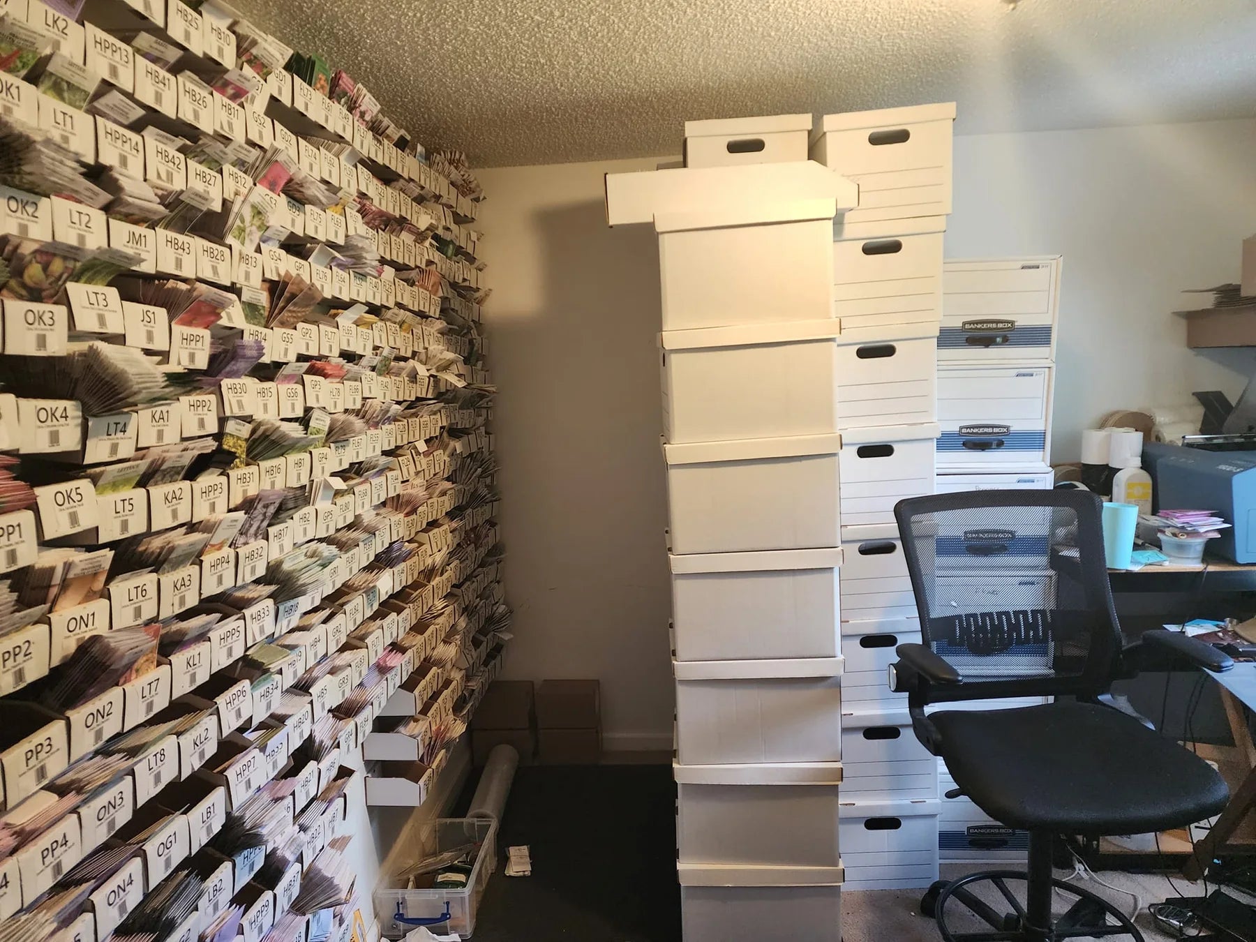 The small bedroom seed room where seed bins, stacked storage boxes, and work equipment filled nearly every wall