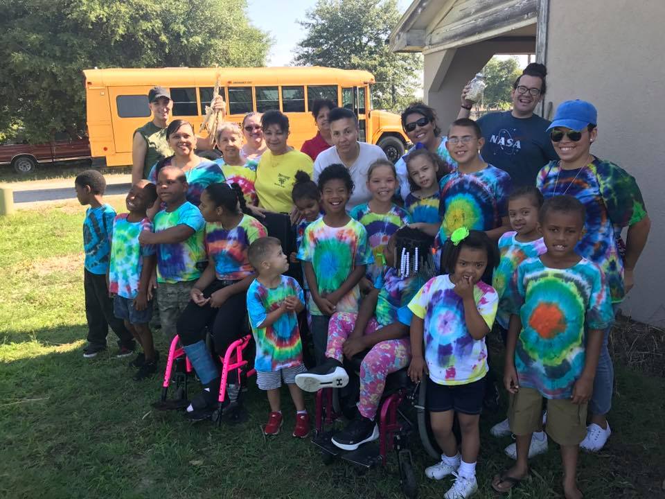 Children and adults gathered together outdoors in colorful shirts