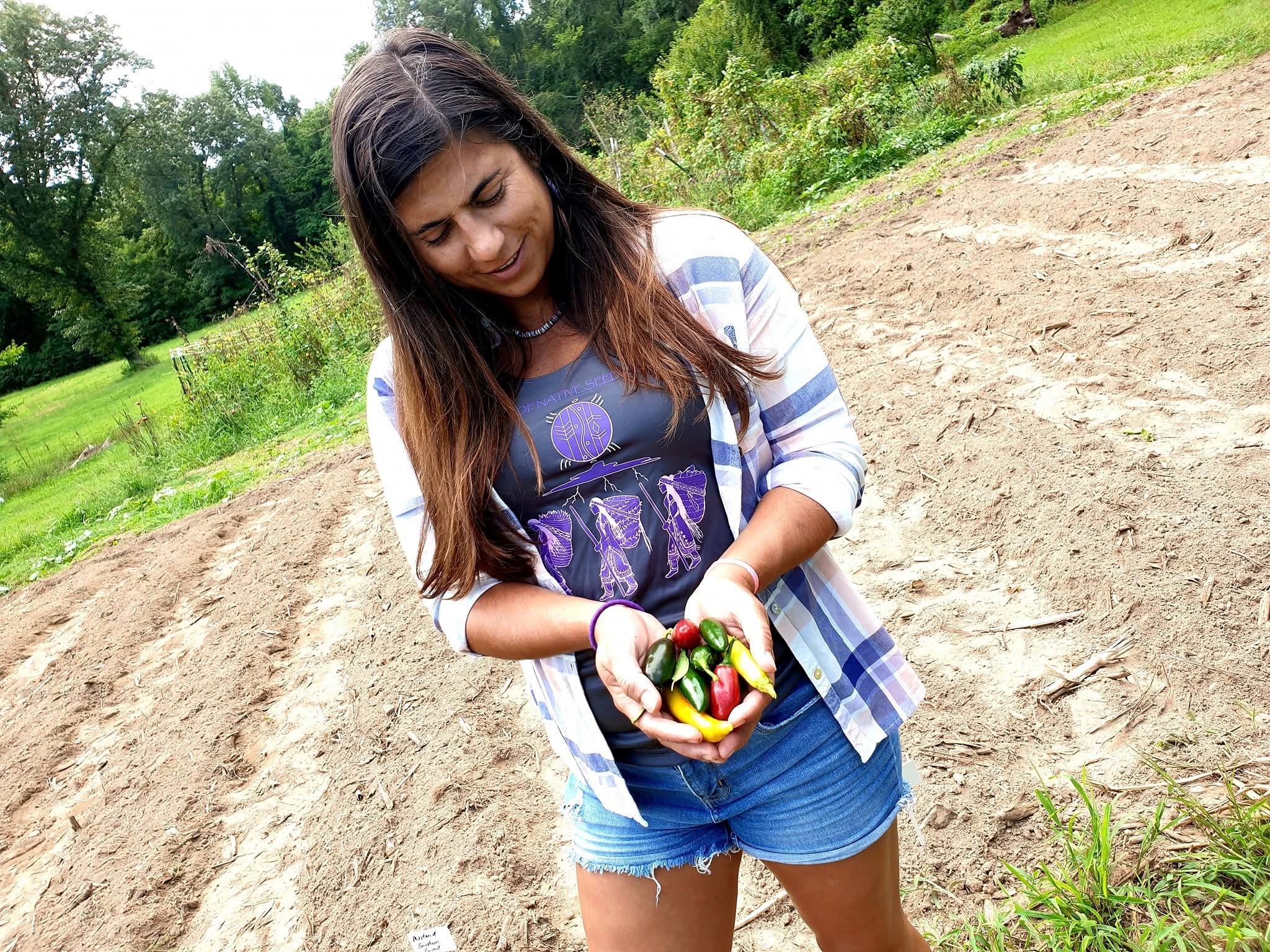 Elizabeth Beth Roach Cain holding colorful peppers in a field in 2019
