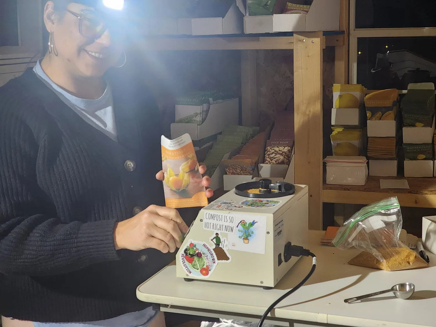 Beth using a headlamp while packing seed orders in the dim seed shed