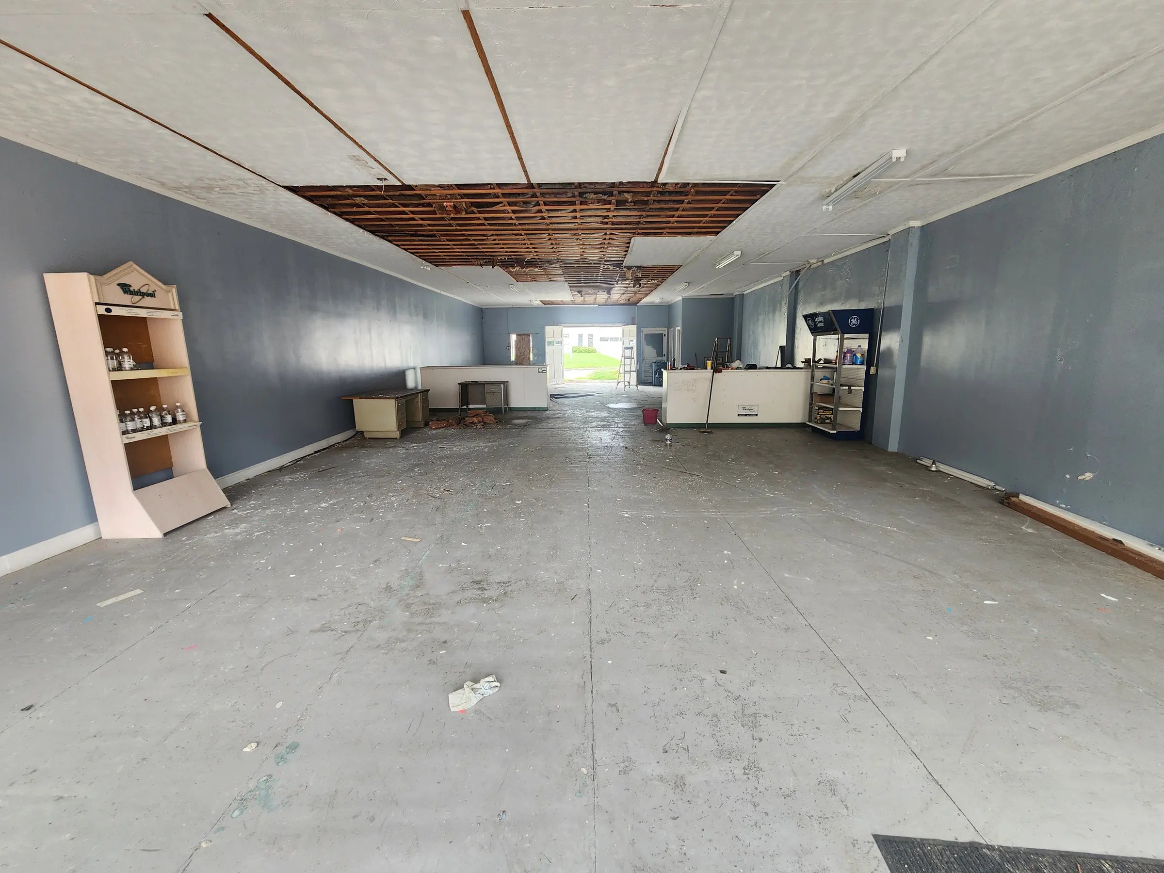 Inside 124 South Main Street before restoration, with open floor space, damaged ceiling sections, and a long neglected interior